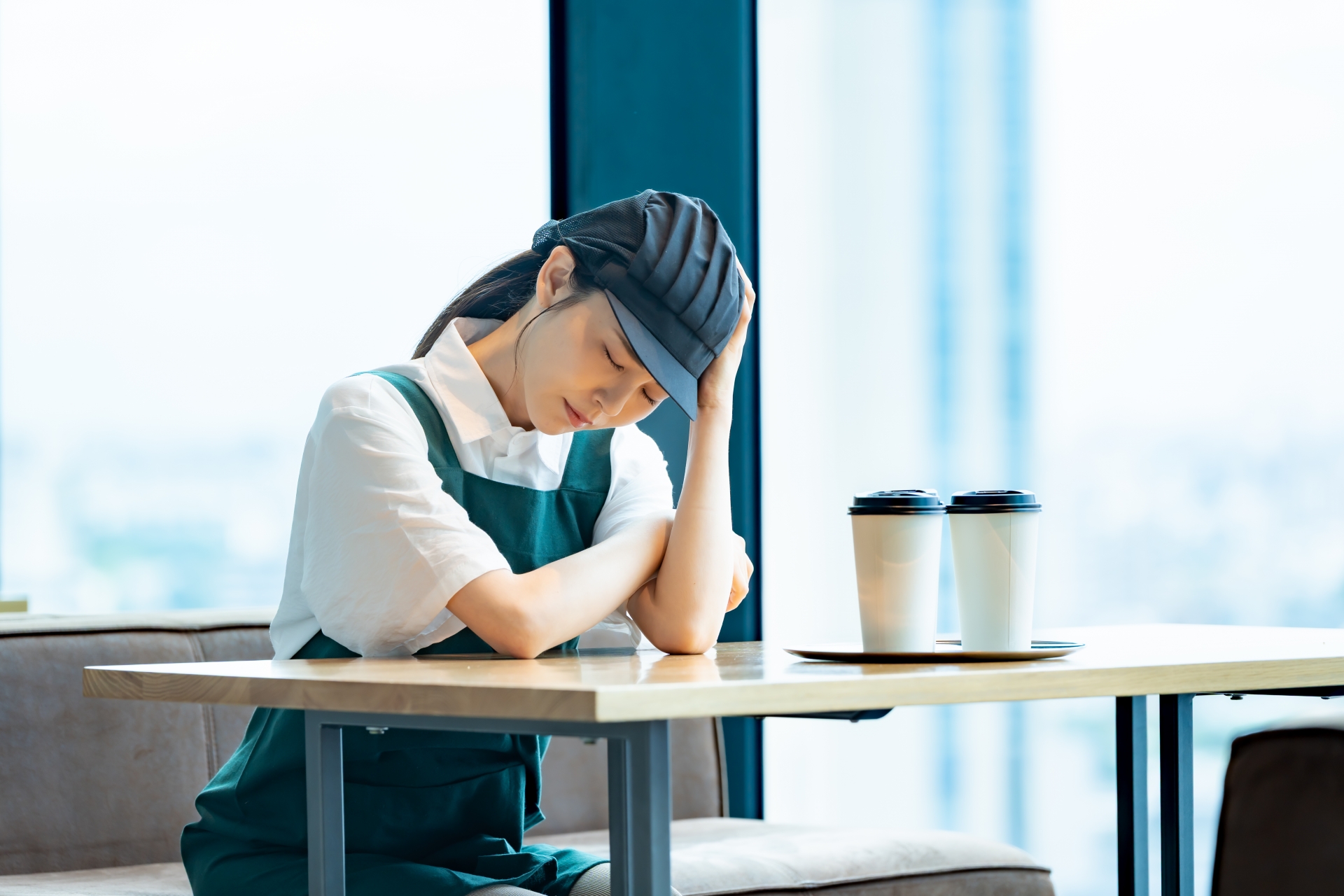 カフェで疲れてうなだれる店員の女性