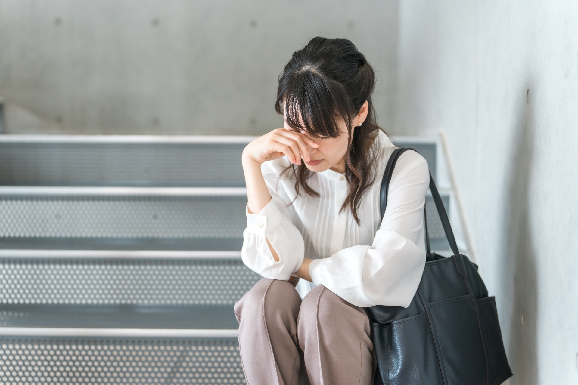 階段に座り込んで落ち込む女性