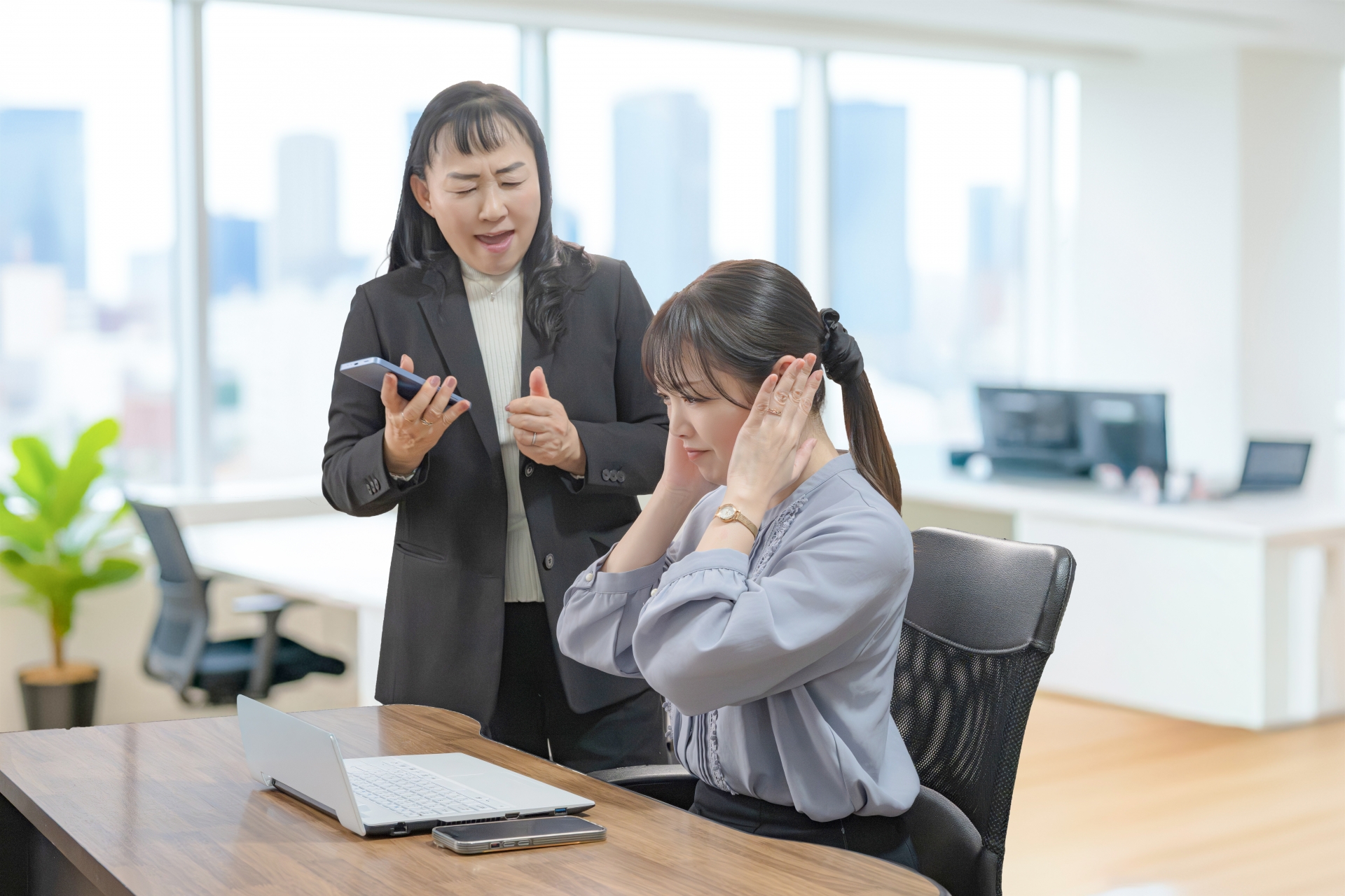 上司に叱られて耳をふさぐ女性