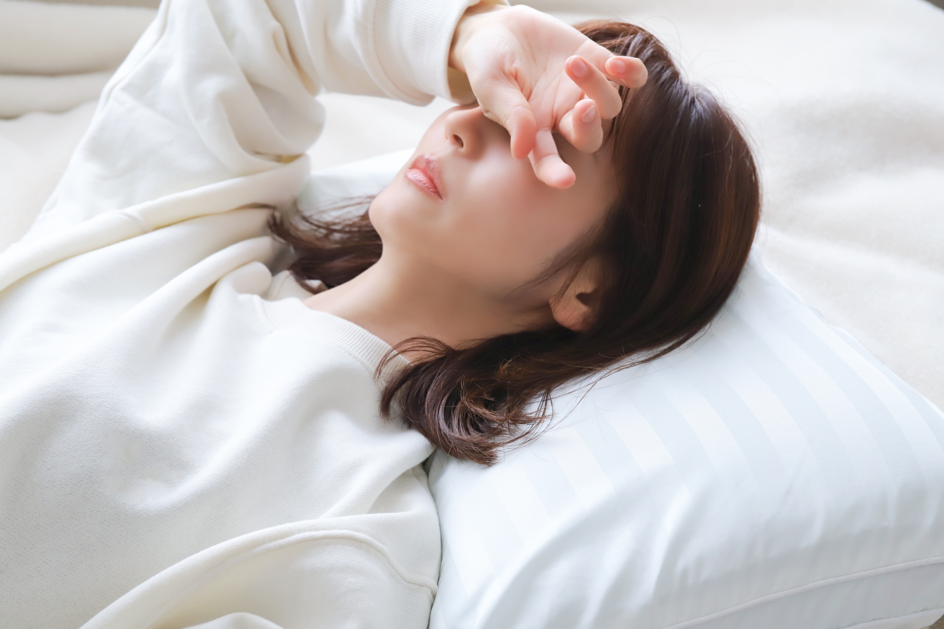 ベッドに横になり疲れた表情の女性